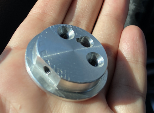a picture of an aluminum CAM, held in a palm.